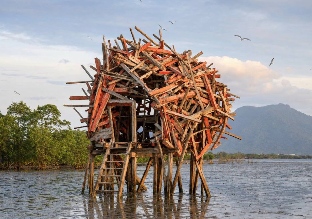A nest-like structure of boat planks standing on stilts in the water