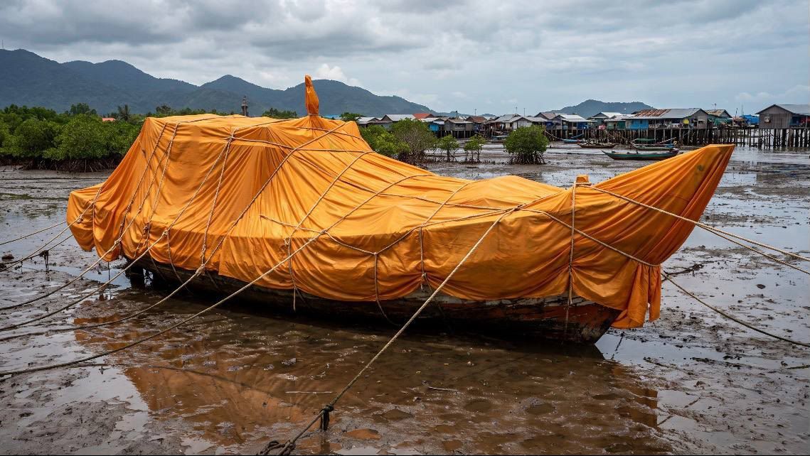 A fishing boat wrapped in orange cloth and bound with rope